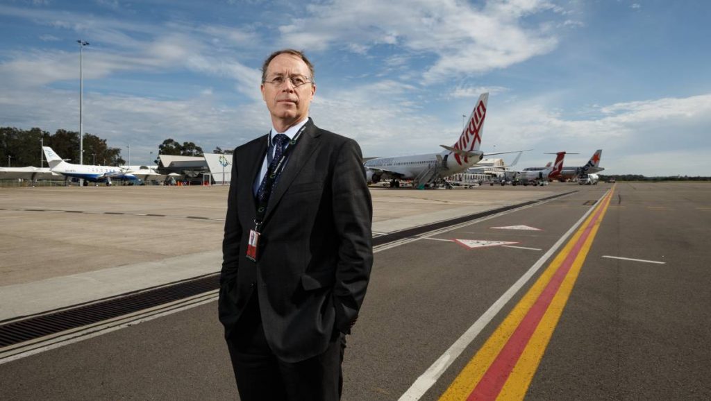 IMAGE: man in suit standing on tarmac at NSW airport