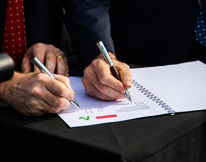 IMAGE: Two hands holding pens to sign on at Astra Aerolab